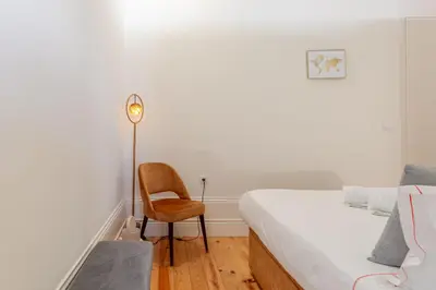 a bedroom with a bed and a chair and a clock at New!! Oporto D Joao IV in Porto
