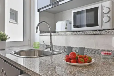 a kitchen counter with a sink and a bowl of strawberries at Crystal Palace House - T2 - D13 in Porto
