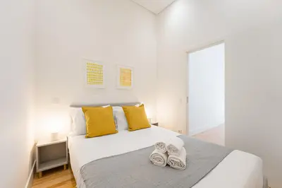 a bedroom with a large white bed with yellow pillows at GuestReady - RNB Apartments in Porto