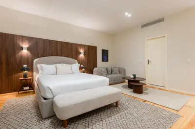 a bedroom with a white bed and a chair at Albertina Carlos Alberto by Aspasios in Porto