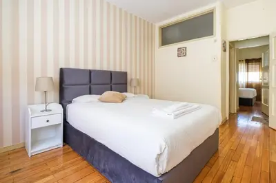 a bedroom with a large bed with a blue headboard at Spacious 3 BRs Apartment, steps to Joao's station in Vila Nova de Gaia