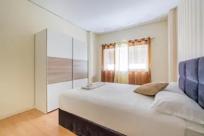 a bedroom with a large bed with a blue chair at Spacious 3 BRs Apartment, steps to Joao's station in Vila Nova de Gaia