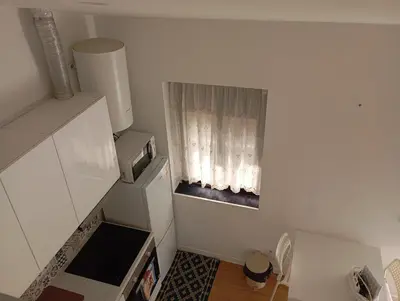 a small white kitchen with a window with curtains at Original Porto - Cedofeita in Porto