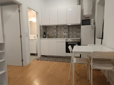 a kitchen with white cabinets and a table and chairs at Original Porto - Cedofeita in Porto