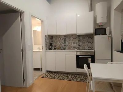 a kitchen with white cabinets and a table and a refrigerator at Original Porto - Cedofeita in Porto