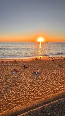 a group of people laying in the sand on the beach at The Arcada House by MyMoradia in Porto
