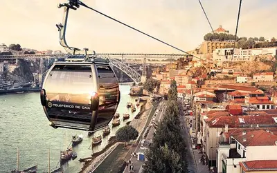 a gondola flying over a city next to a river at Cais das Flores in Vila Nova de Gaia