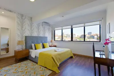 a bedroom with a bed and a desk and a window at APOSENTUS - The First in Porto