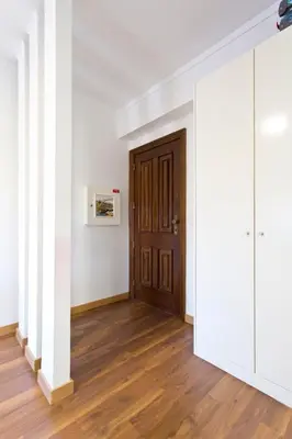 a hallway with a wooden door and white walls at APOSENTUS - The First in Porto