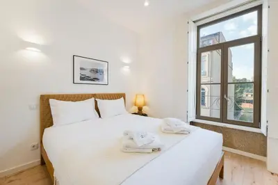 a bedroom with a large white bed and a window at GuestReady - A lovely stay in Rua da Boavista in Porto