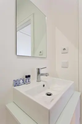 a white bathroom with a sink and a mirror at APOSENTUS - Porto's Charming Apartment in Porto