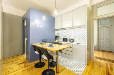 a kitchen with a wooden table and a blue wall at 741 Studio By D&S in Porto