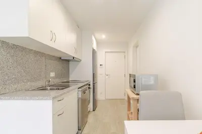 a white kitchen with a sink and a counter at HostWise - Modern & Bright Studio in Porto