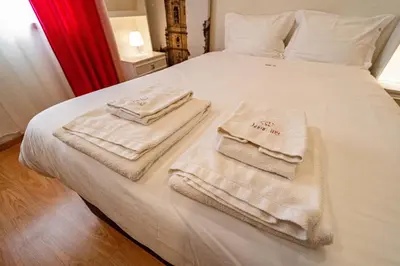 a bed with three towels sitting on top of it at O'Porto Main Street St Catarina 2 Studio Apartment in Porto