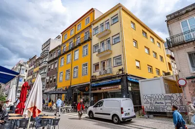 a white car parked in front of a yellow building at O'Porto Main Street St Catarina 2 Studio Apartment in Porto