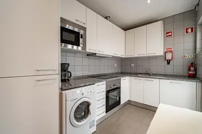 a kitchen with white cabinets and a washer and dryer at O'Porto Main Street St Catarina 2 Studio Apartment in Porto
