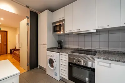 a kitchen with white cabinets and a washer and dryer at O'Porto Main Street St Catarina 2 Studio Apartment in Porto