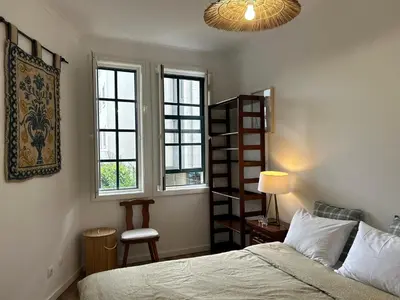 a bedroom with a bed and two windows at O Alecrim in Porto