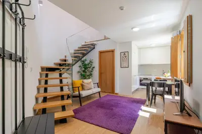 a living room with a purple rug and a spiral staircase at Host Wise Stylish Studio with Garage in Porto