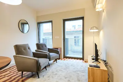 a living room with two chairs and a television at VIVA Ildefonso Serviced Apartments in Porto