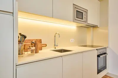 a kitchen with white cabinets and a sink at VIVA Ildefonso Serviced Apartments in Porto