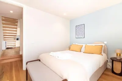 a white bedroom with a white bed with yellow pillows at Miguel Bombarda House in Porto