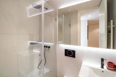 a white bathroom with a shower and a sink at Miguel Bombarda House in Porto