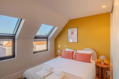 a bedroom with a white bed with two windows at Miguel Bombarda House in Porto