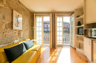 a living room with a yellow couch and large windows at Cedofeita Back Garden in Porto