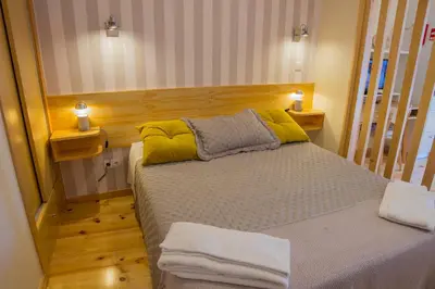 a small bedroom with a bed with yellow pillows at Cedofeita Back Garden in Porto