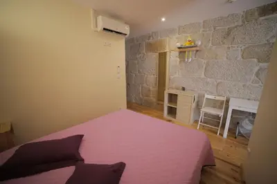 a bedroom with a pink bed and a stone wall at Cedofeita Back Garden in Porto
