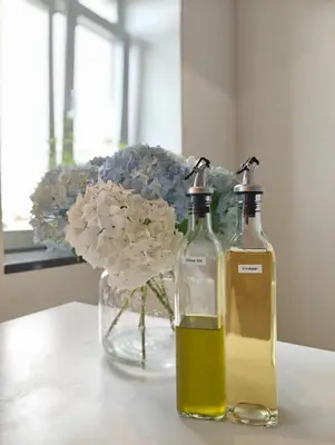 two bottles of oil next to a vase of flowers at Castelo River View - NEW in Vila Nova de Gaia
