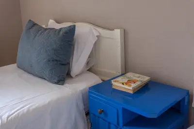 a blue nightstand next to a bed with a book on it at Being Porto Hostel in Porto