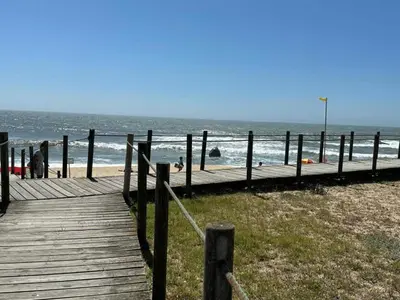 a wooden boardwalk on the beach with people in the water at Feel Porto Bacchus Townhouse in Porto