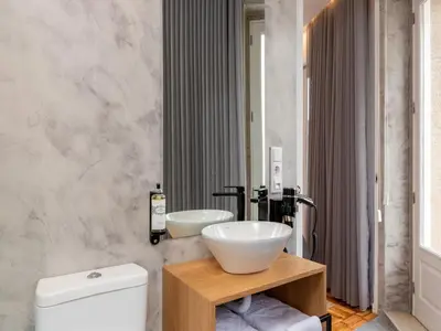 a bathroom with a sink and a toilet and a mirror at Feel Porto Bacchus Townhouse in Porto