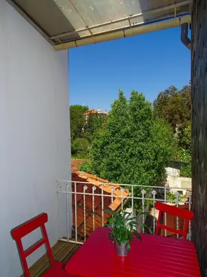 a red table and two chairs on a balcony at O2 Hostel in Porto