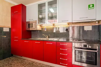 a red kitchen with white cabinets and a sink at Petit Suites by PCALE in Porto