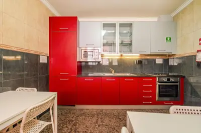 a red kitchen with white cabinets and a microwave at Petit Suites by PCALE in Porto