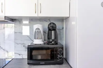 a black microwave with a coffee maker on top of it at Gaia Family Nest in Vila Nova de Gaia