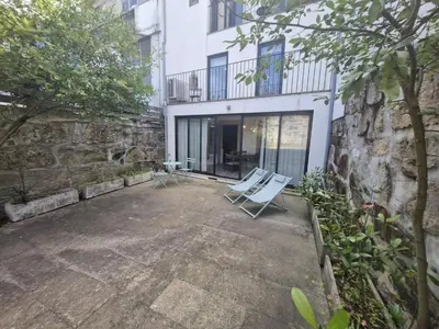 a patio with two white chairs in front of a building at Campanhã Clock House with terrace in Porto