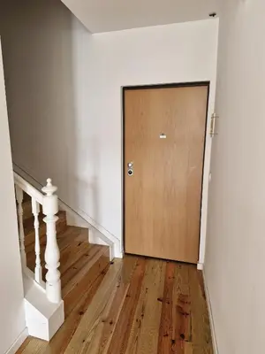 an empty hallway with a wooden door and stairs at Campanhã Clock House with terrace in Porto
