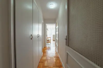 a hallway with white walls and wood floors and a mirror at Cedofeita Terrace by Hosty in Porto