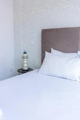 a white bed with a white pillow and a night stand at Happy's Apartments in Porto
