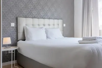 a large bed with white sheets and pillows at Happy's Apartments in Porto