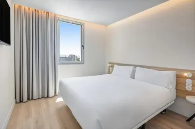 a white bedroom with a large bed and a window at B&B HOTEL Porto Centro Massarelos in Porto