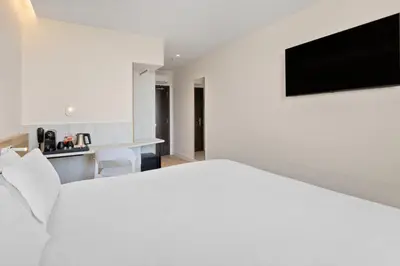a bedroom with a white bed and a television on the wall at B&B HOTEL Porto Centro Massarelos in Porto