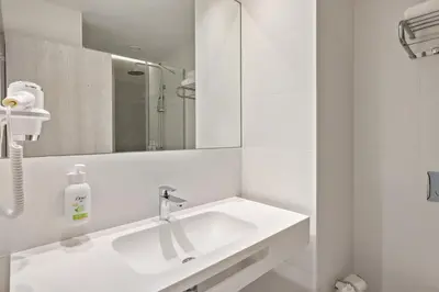 a white bathroom with a sink and a mirror at B&B HOTEL Porto Centro Massarelos in Porto