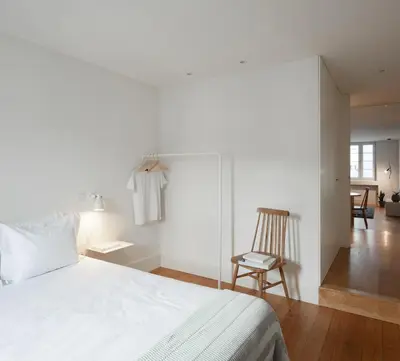 a bedroom with a white bed and a chair at Santa Catarina 555 T4 in Porto