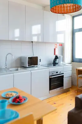 a kitchen with white cabinets and a table with plates of food at Groovy Porto by Upperground in Porto