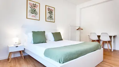 a white bedroom with a white bed and two chairs at Green House Apartamento Espaçoso e Central in Porto